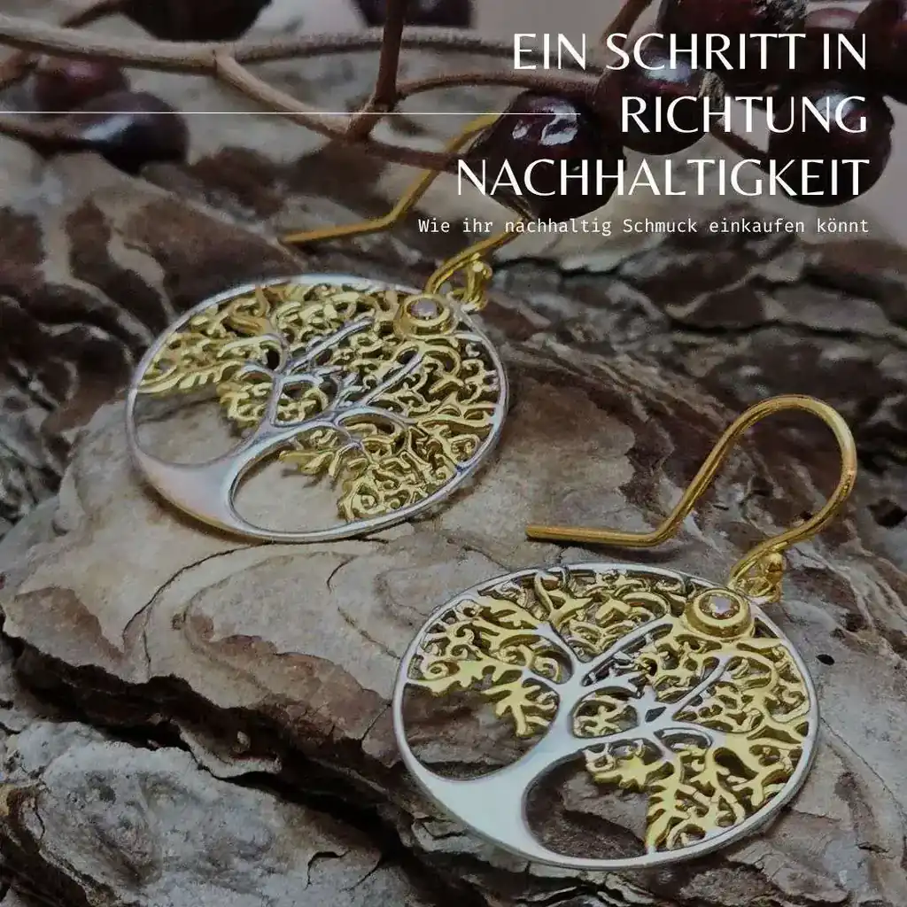 Ein Paar runde Ohrhänger aus Silber mit einem filigranen Lebensbaum-Motiv, teils vergoldet. Die Ohrringe liegen auf einer natürlichen Holzoberfläche, umgeben von kleinen Zweigen. Der Text „EIN SCHRITT IN RICHTUNG NACHHALTIGKEIT – Wie ihr nachhaltig Schmuck einkaufen könnt“ steht in der oberen rechten Ecke des Bildes.